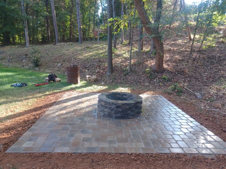 finished stone fire pit with custom paver patio in charlotte nc surrounded by trees for outdoor entertaining and relaxation