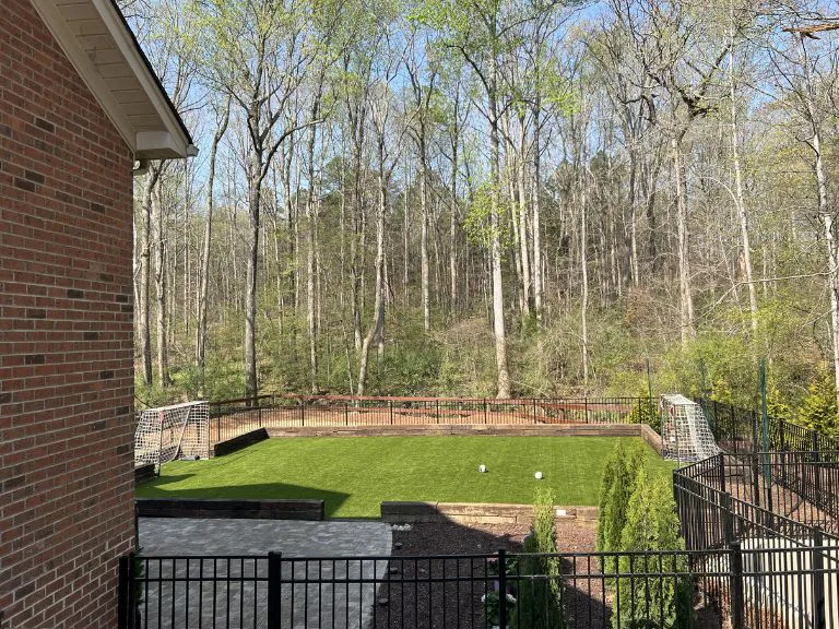 walled artificial turf field with soccer goals and wooded backdrop beside a brick house in fort mill, sc