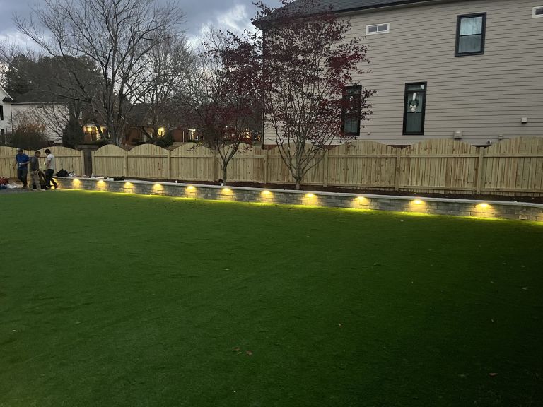 Wide-angle view of completed Fort Mill SC backyard renovation with turf, walls, and walkway — CLT Pros project