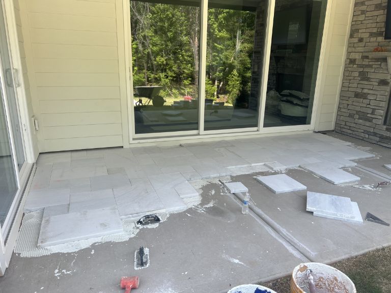 white marble pavers being set across the covered patio slab in indian land, sc