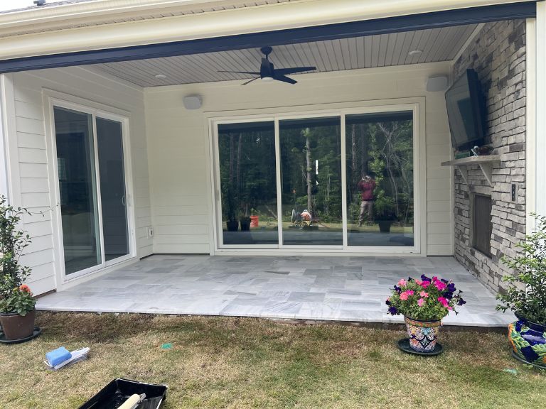 white marble patio under a covered porch with stone wall and ceiling fan in indian land, sc