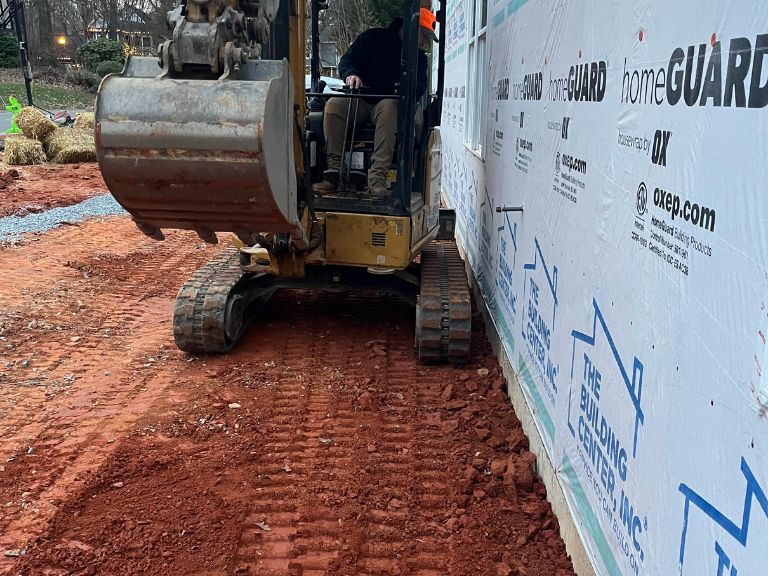 mini excavator precision grading soil against foundation wall in matthews, nc