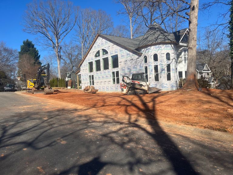wide view of graded yard and cleared soil beside completed home exterior in matthews, nc