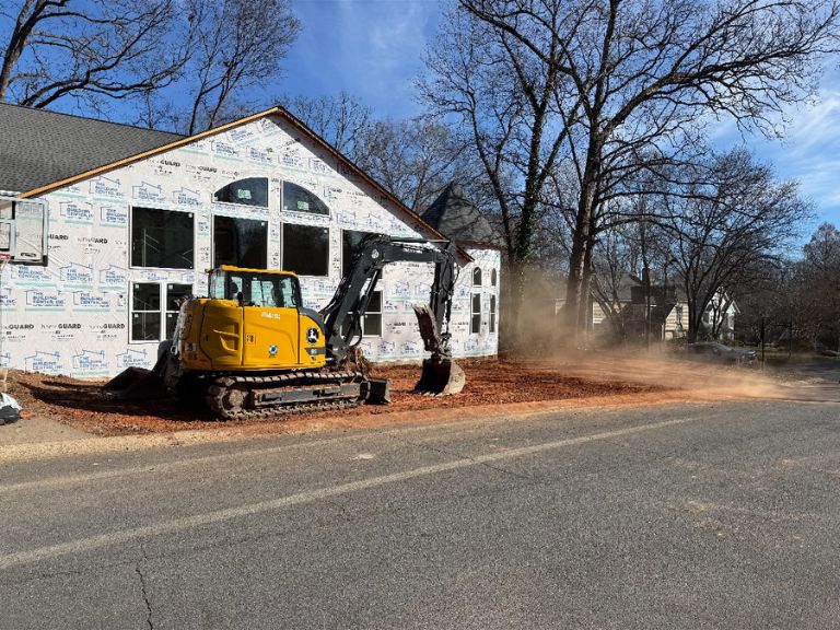 excavator grading soil near foundation with dust from dry clay in matthews, nc