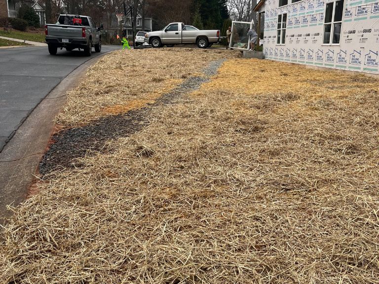 straw-covered graded yard with drainage swale after grading project in matthews, nc