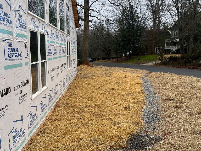 side yard with straw-covered graded soil and gravel drainage channel in matthews, nc