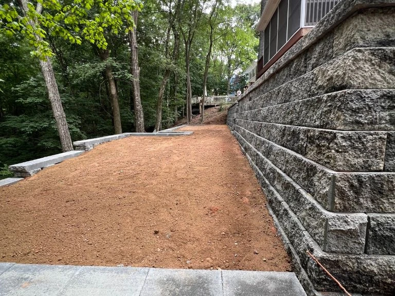 first-tier terraced retaining wall constructed from large granite-face segmental blocks with graded clay soil base in tega cay sc — clt pros