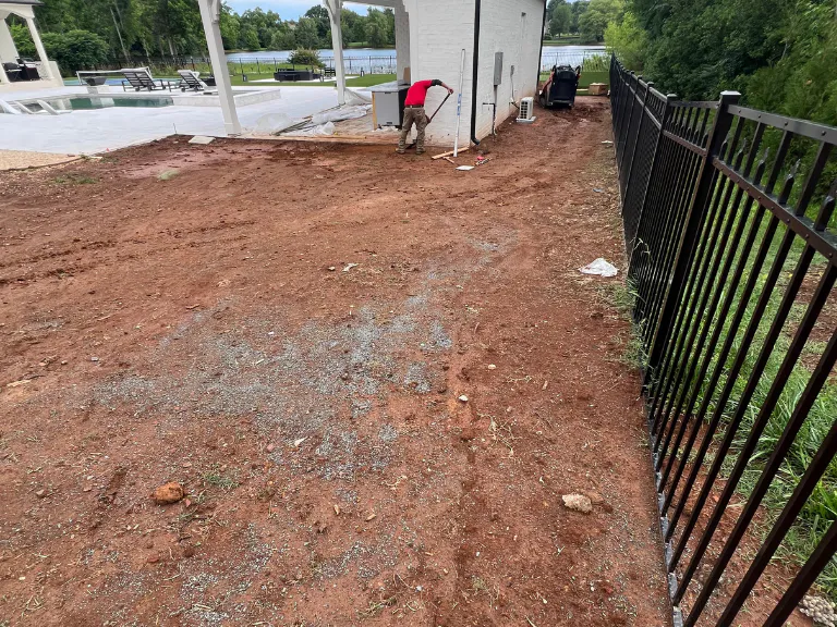 bare red clay side yard along an iron fence before artificial turf installation in weddington, nc