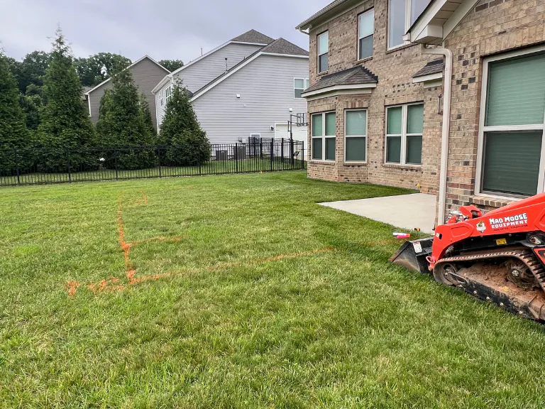 open lawn behind a brick home marked out for a new paver patio in weddington, nc