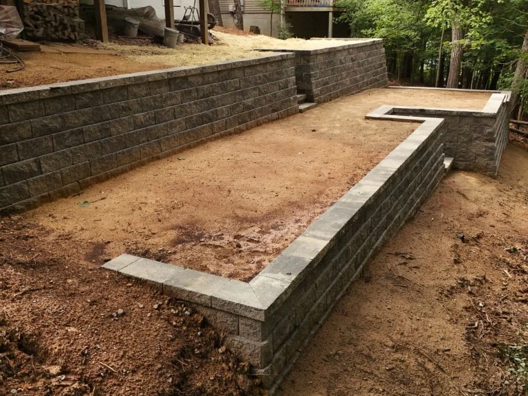 ground-level view of completed lower retaining wall with coping cap and rectangular turf zone framed by walls in tega cay sc — clt pros