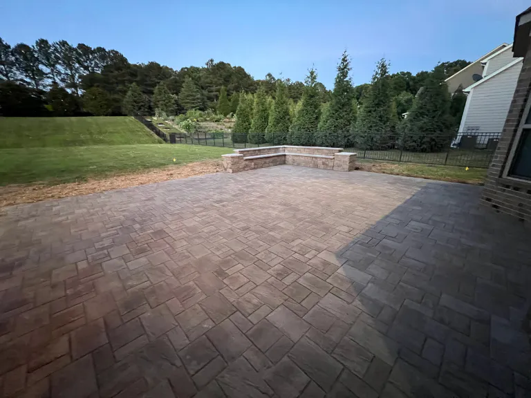 paver patio and seating wall facing the tree line at dusk in weddington, nc