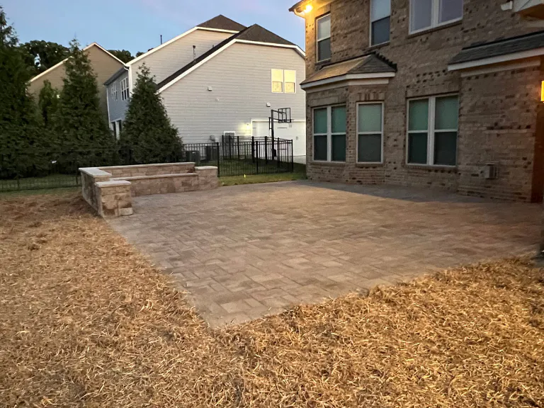 finished paver patio and seating wall framed by pine straw beside the house in weddington, nc