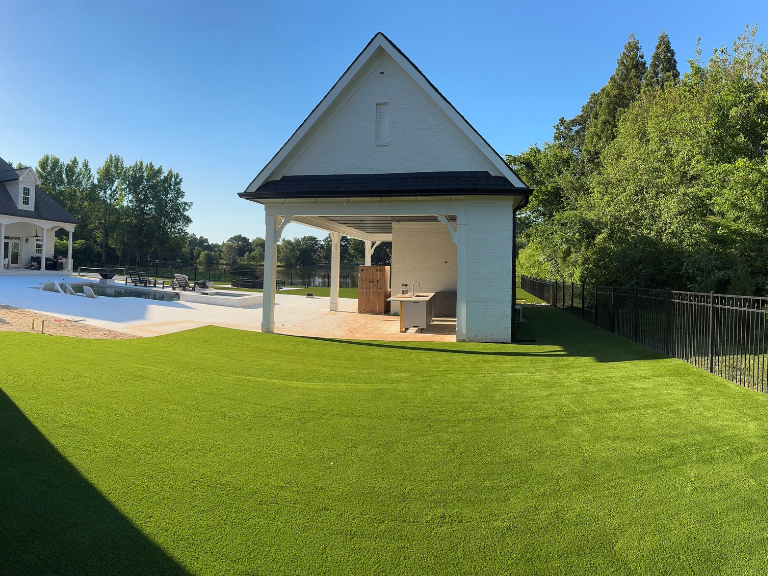 wide view of the finished artificial turf backyard and pool house in weddington, nc