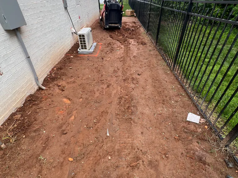 graded clay side yard beside the house and ac unit before turf and drainage work in weddington, nc