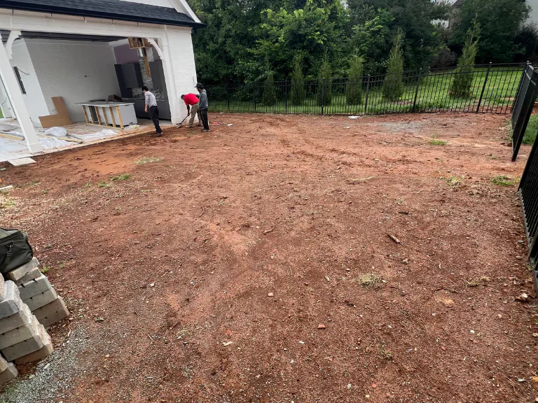 bare clay yard beside the pool house patio before turf and drainage installation in weddington, nc