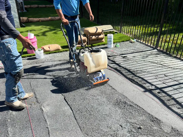 crew compacting the stone base with a plate compactor before laying artificial turf in weddington, nc