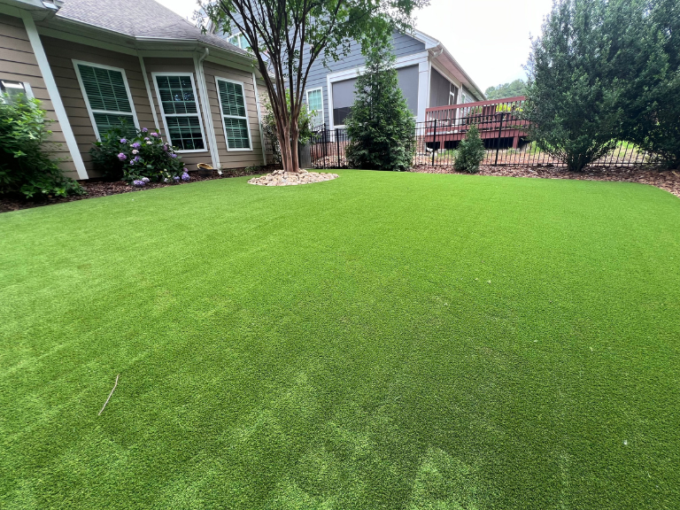 Completed artificial turf installation in Tega Cay SC backyard with full lawn and iron fence — CLT Pros York County