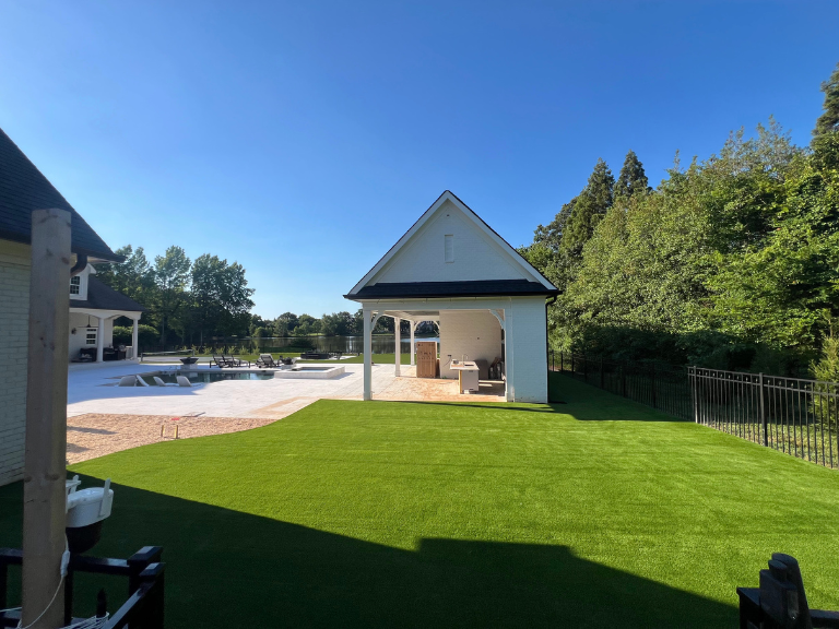 Completed artificial turf in Weddington NC luxury backyard with pergola, outdoor kitchen, and lakefront pool — CLT Pros Union County