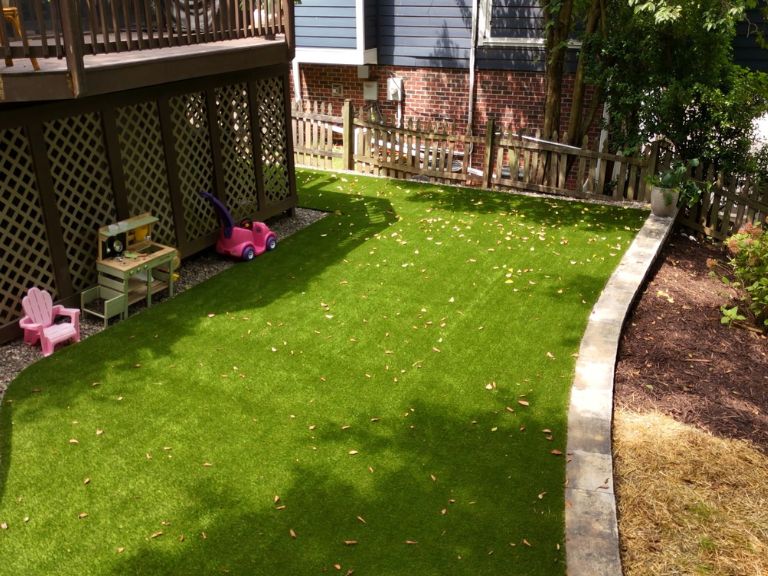 street-level view of completed artificial turf area with curved segmental block border wall, mulch planting beds, and deck above in plaza midwood charlotte nc — clt pros