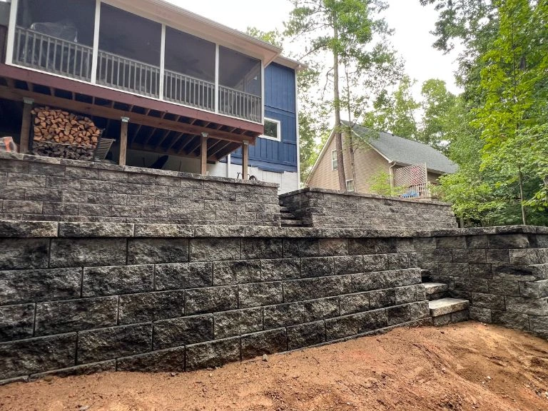 upper retaining wall tier with integrated steps below raised screened porch on wooded tega cay sc lot — clt pros