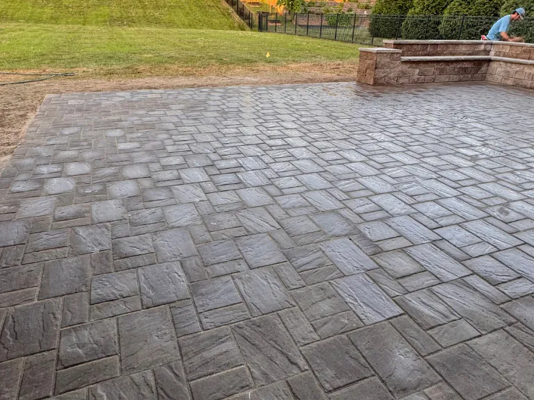 paver patio corner with the stone seating wall and iron fence in weddington, nc