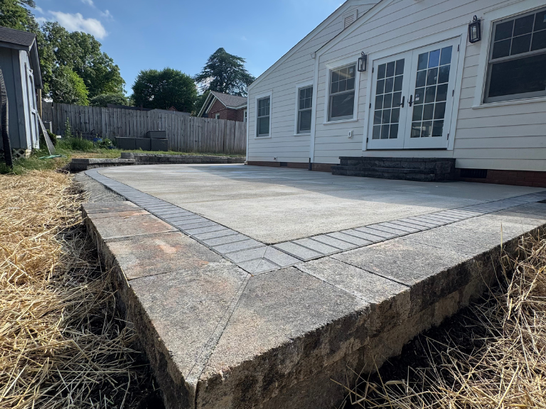 Completed concrete patio with curved paver border and retaining wall at South End Charlotte NC — CLT Pros hardscape