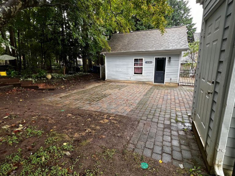 weathered paver patio with moss and weeds between the house and detached garage in huntersville, nc