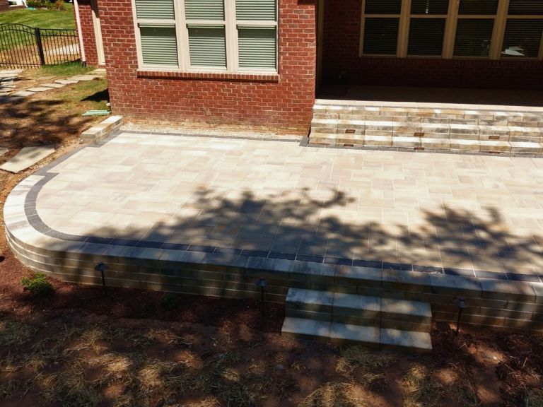 raised paver patio with retaining wall steps and lit paver steps to the covered porch in indian land, sc