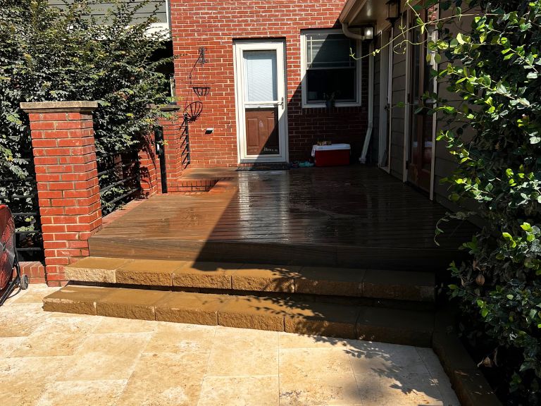 travertine patio and stained wood deck steps beside brick columns at a grier heights home in charlotte, nc