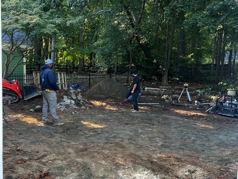 clt pros crew grading the backyard with a laser level before the concrete pour in huntersville, nc