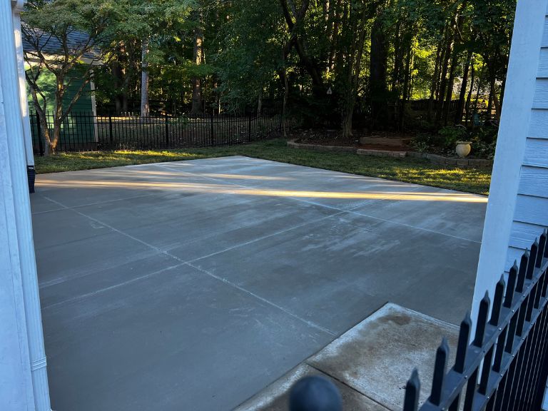 finished broom-finish concrete patio with control joints seen from the side gate in huntersville, nc