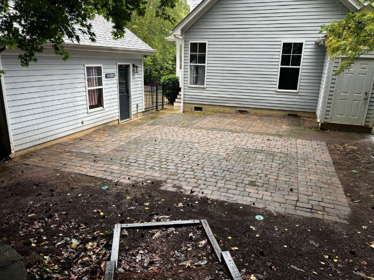 aging paver patio and rotted timber garden edging behind a huntersville, nc home before demolition