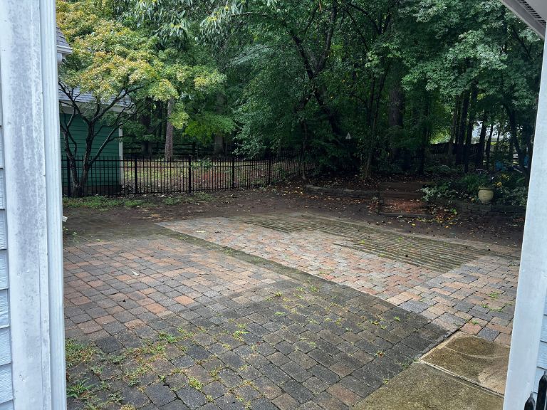 sunken, moss-stained paver patio along the side of the house facing the wooded backyard in huntersville, nc