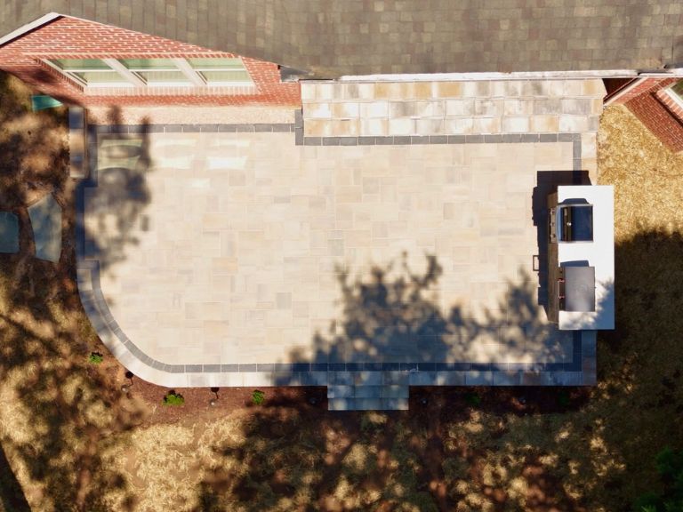 high-angle drone view of a raised paver patio with charcoal border and grill island in indian land, sc