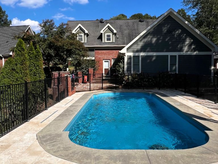 pool surrounded by travertine pavers and a black aluminum pool fence in grier heights, charlotte, nc
