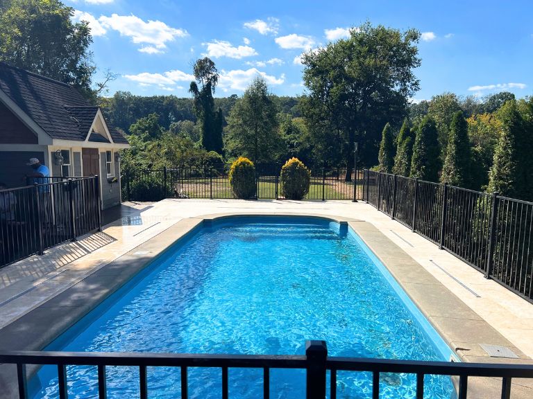 full view of the pool, travertine deck, and black aluminum pool fence in grier heights, charlotte, nc